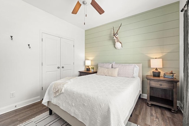 bedroom featuring wood walls, a closet, wood finished floors, and baseboards