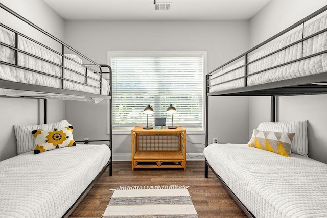 bedroom featuring visible vents, baseboards, and wood finished floors