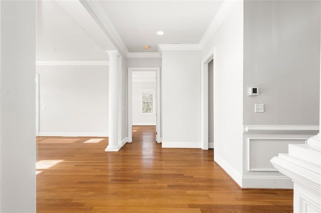 corridor with hardwood / wood-style flooring, ornamental molding, and ornate columns