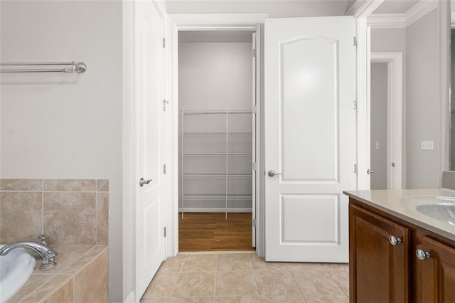 bathroom with tile patterned flooring, vanity, and a relaxing tiled tub