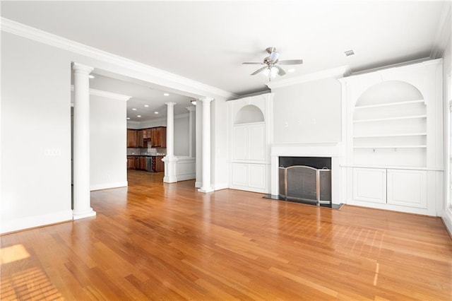 unfurnished living room featuring ceiling fan, hardwood / wood-style floors, decorative columns, ornamental molding, and built in shelves