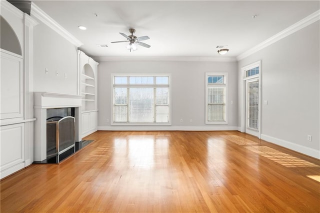 unfurnished living room featuring crown molding, light hardwood / wood-style floors, built in shelves, and a healthy amount of sunlight