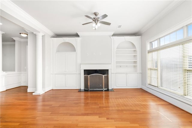 unfurnished living room featuring built in shelves, crown molding, light hardwood / wood-style floors, and decorative columns