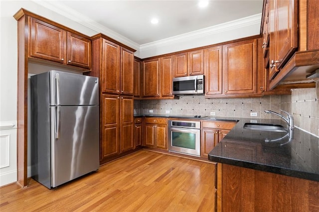 kitchen featuring sink, dark stone countertops, stainless steel appliances, light hardwood / wood-style floors, and backsplash