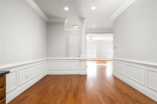 spare room with ornate columns, ceiling fan, ornamental molding, and light wood-type flooring