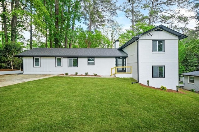 view of front of home with board and batten siding, a chimney, and a front yard