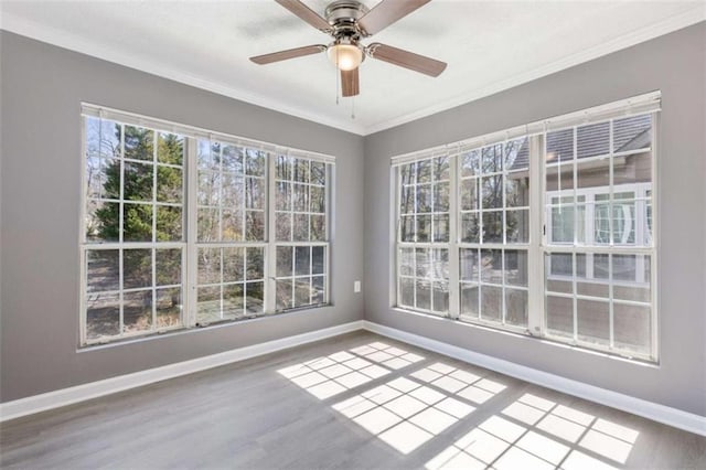 interior space featuring wood finished floors, baseboards, ornamental molding, and ceiling fan