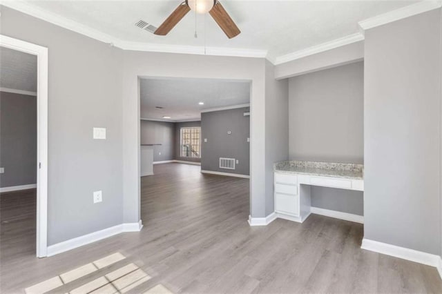 interior space featuring crown molding, a ceiling fan, visible vents, and built in study area