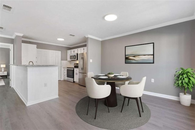 dining space with visible vents, ornamental molding, baseboards, and wood finished floors