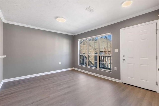 foyer entrance with ornamental molding, wood finished floors, visible vents, and baseboards