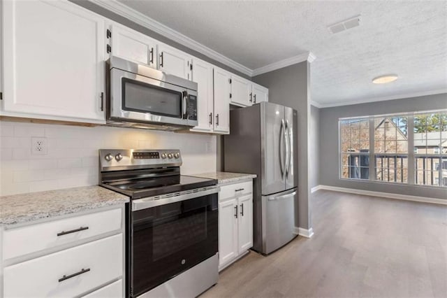 kitchen with stainless steel appliances, visible vents, ornamental molding, and white cabinets