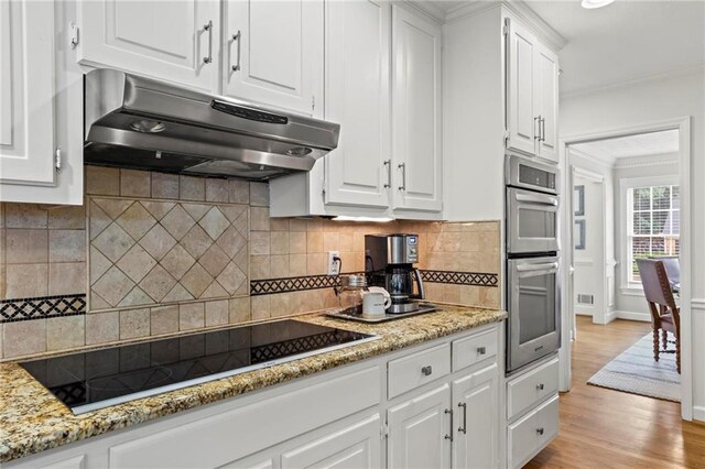 4792 Fairville Ct, Marietta, GA 30062 - kitchen with under cabinet range hood, black electric cooktop, stainless steel double oven, white cabinets, and ornamental molding