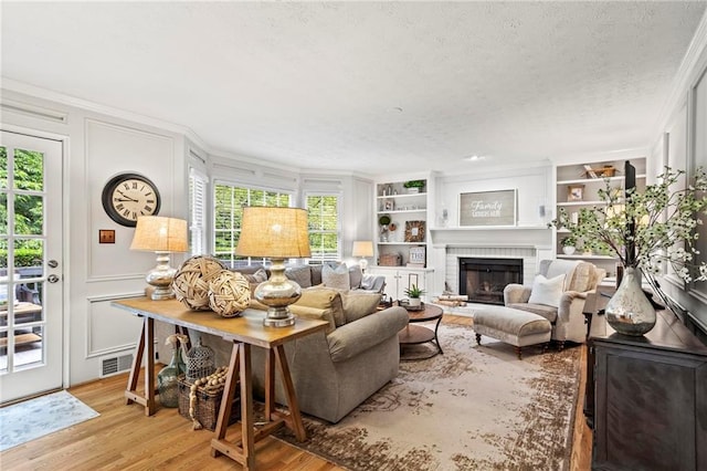 4792 Fairville Ct, Marietta, GA 30062 - living area with ornamental molding, a decorative wall, wood finished floors, built in shelves, and a fireplace