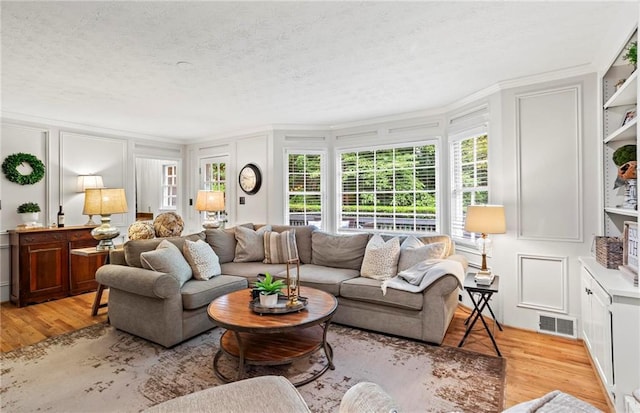 4792 Fairville Ct, Marietta, GA 30062 - living area featuring a decorative wall, light wood finished floors, plenty of natural light, crown molding, and a textured ceiling