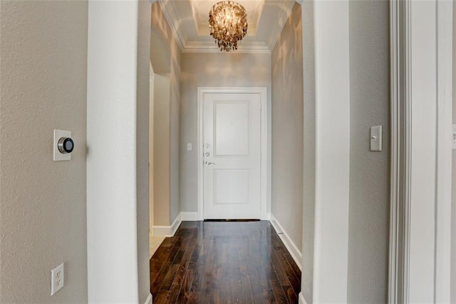 hall featuring a notable chandelier, dark wood-type flooring, and ornamental molding