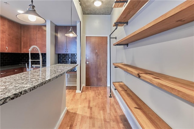 kitchen featuring wood counters, sink, light hardwood / wood-style flooring, pendant lighting, and decorative backsplash