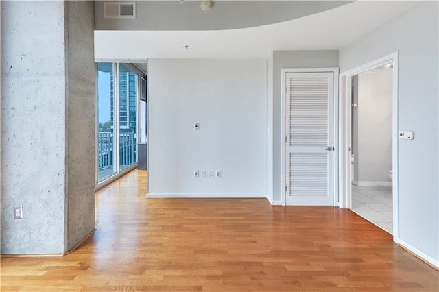 spare room featuring a wall of windows and light hardwood / wood-style flooring