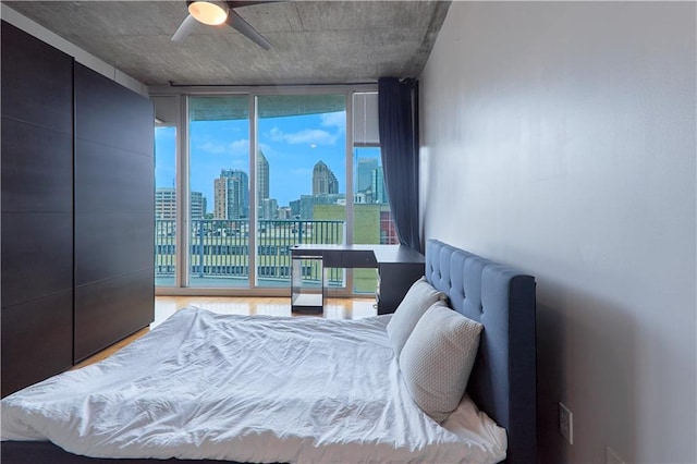 bedroom featuring wood-type flooring, access to outside, ceiling fan, and a wall of windows