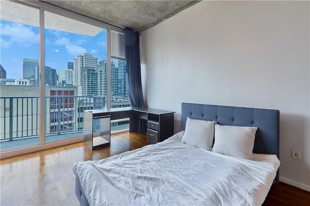 bedroom with a wall of windows and dark hardwood / wood-style flooring