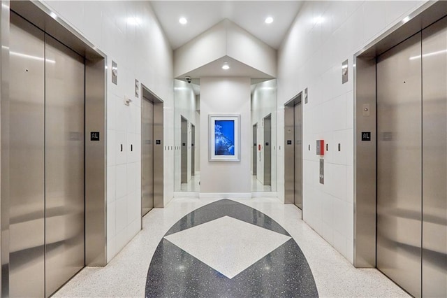 hallway featuring a package area, elevator, and tile walls