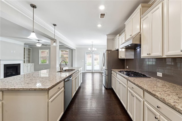 4090 Danbury Farms Dr, Cumming, GA 30040 - kitchen featuring a sink, under cabinet range hood, appliances with stainless steel finishes, backsplash, and a glass covered fireplace