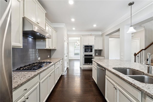 4090 Danbury Farms Dr, Cumming, GA 30040 - kitchen featuring under cabinet range hood, a sink, stainless steel appliances, crown molding, and backsplash