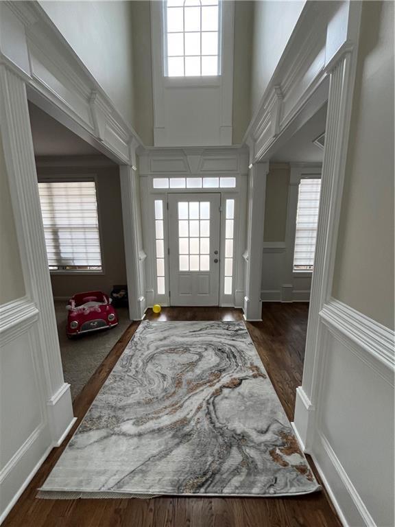 foyer entrance featuring a towering ceiling, dark hardwood / wood-style flooring, and a wealth of natural light