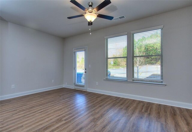 unfurnished room featuring plenty of natural light, ceiling fan, and dark hardwood / wood-style floors