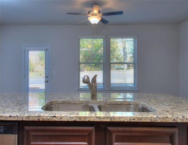 interior details with light stone counters, dishwasher, ceiling fan, and sink