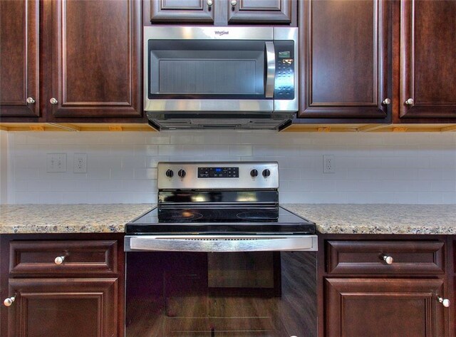 kitchen featuring appliances with stainless steel finishes, light stone counters, decorative backsplash, and dark brown cabinetry