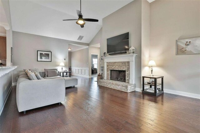 living room featuring ceiling fan, dark hardwood / wood-style flooring, high vaulted ceiling, and a brick fireplace