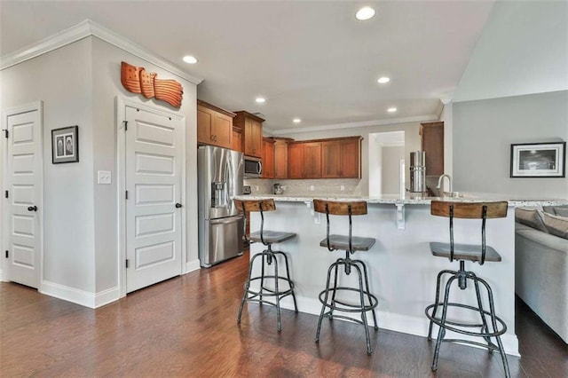 kitchen with kitchen peninsula, a kitchen breakfast bar, light stone countertops, stainless steel appliances, and crown molding