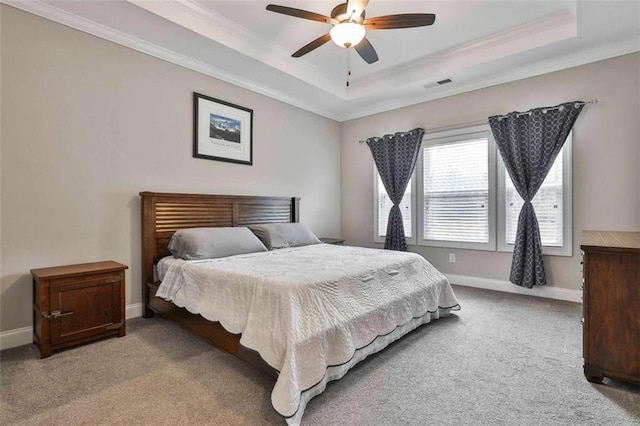 carpeted bedroom with a tray ceiling, ceiling fan, and ornamental molding