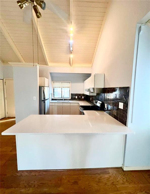 kitchen featuring dark hardwood / wood-style floors, kitchen peninsula, stainless steel appliances, and wood ceiling