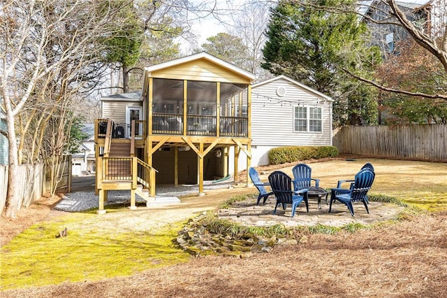 rear view of house featuring a patio, a sunroom, a yard, and a fire pit