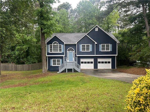 bi-level home with an attached garage, concrete driveway, and view of scattered trees