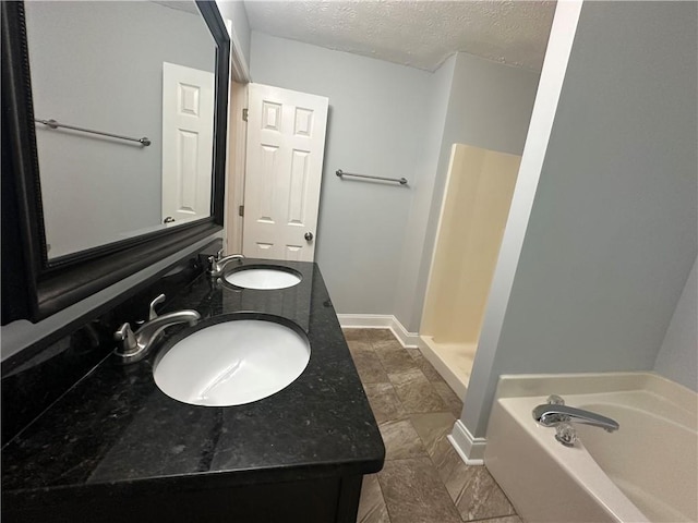 bathroom featuring a textured ceiling, a bath, baseboards, double vanity, and a shower
