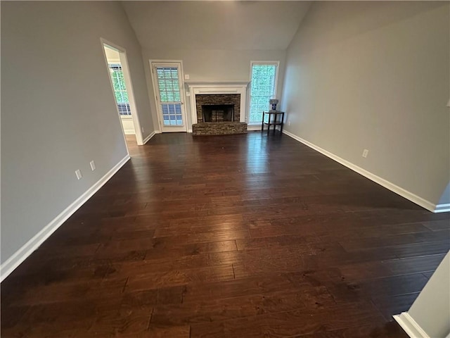 unfurnished living room with lofted ceiling, healthy amount of natural light, baseboards, and dark wood finished floors