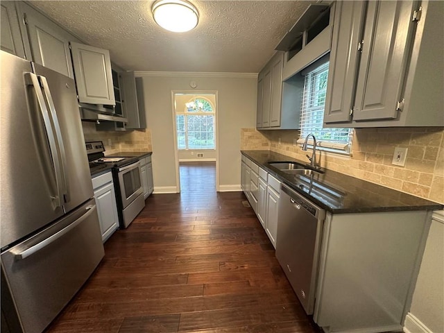 kitchen featuring appliances with stainless steel finishes, a sink, gray cabinets, a textured ceiling, and crown molding