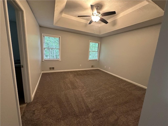 carpeted spare room with a tray ceiling, baseboards, and a ceiling fan