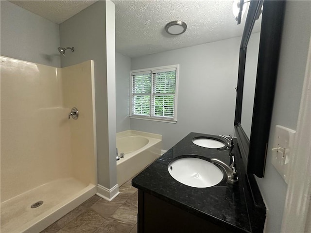 bathroom featuring a shower stall, a bath, a textured ceiling, and double vanity