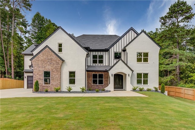 modern farmhouse featuring brick siding, board and batten siding, a front yard, and fence