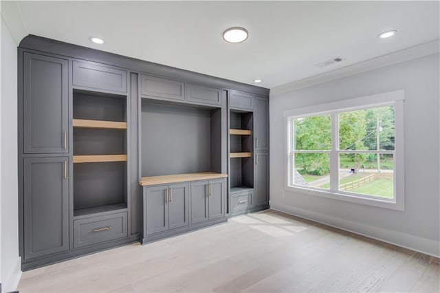 unfurnished living room featuring light wood finished floors, visible vents, built in shelves, baseboards, and recessed lighting