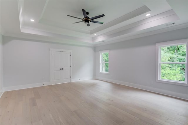 empty room featuring visible vents, light wood-style flooring, recessed lighting, baseboards, and a raised ceiling