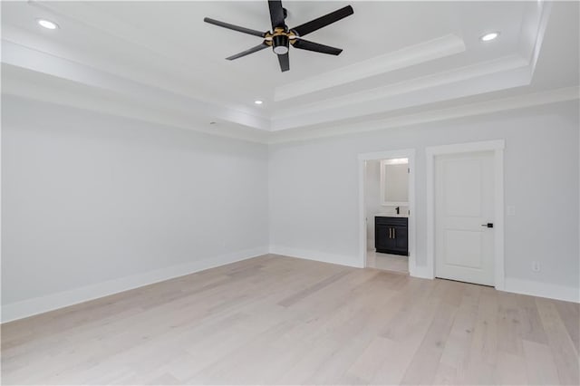 unfurnished room featuring baseboards, a tray ceiling, recessed lighting, ornamental molding, and light wood-style floors