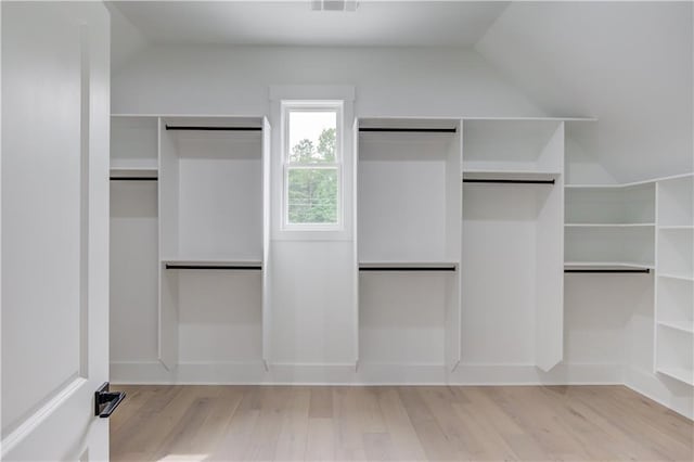 walk in closet featuring visible vents, lofted ceiling, and wood finished floors