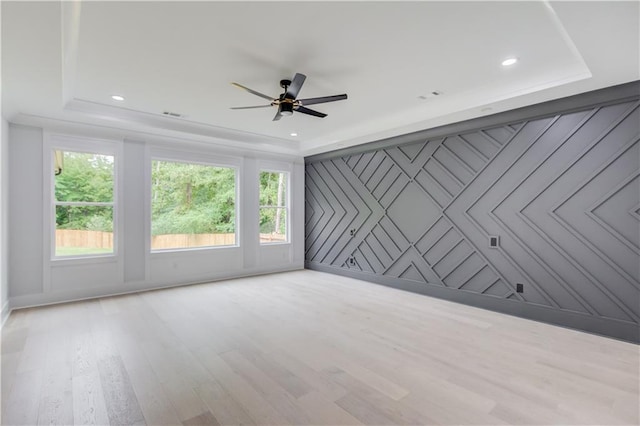 unfurnished room featuring a tray ceiling, recessed lighting, and wood finished floors