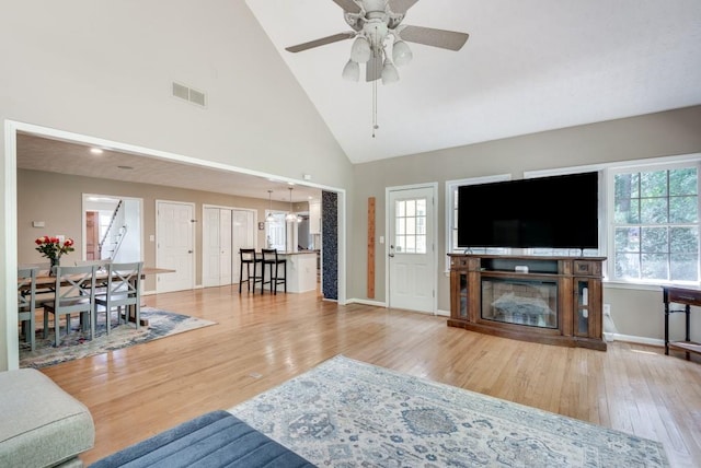 living room with ceiling fan, light hardwood / wood-style flooring, high vaulted ceiling, and plenty of natural light