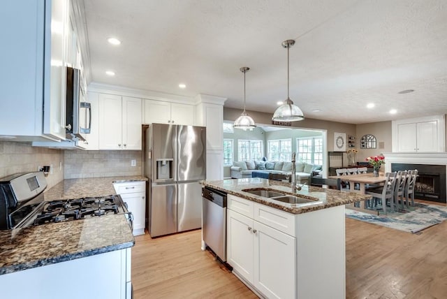 kitchen featuring white cabinetry, a kitchen island with sink, light wood-type flooring, and appliances with stainless steel finishes