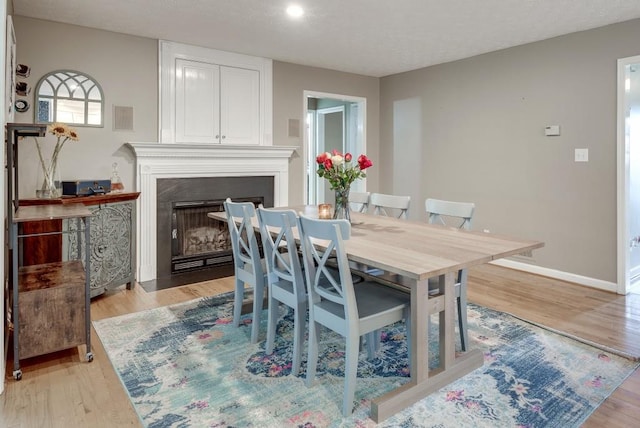 dining room with a fireplace and light hardwood / wood-style flooring